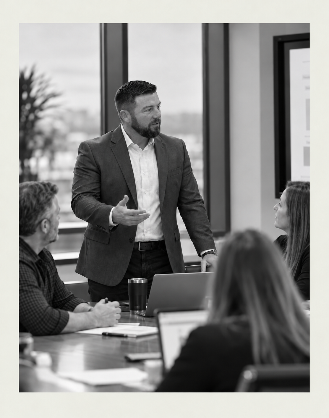 Editorial-style black-and-white illustration of Mathon Bates collaborating with a team in a business meeting